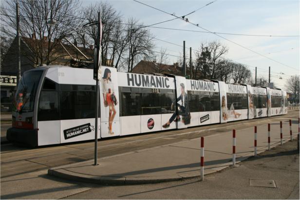Eine Straßenbahn mit Werbung für HUMANIC fährt durch die Stadt.