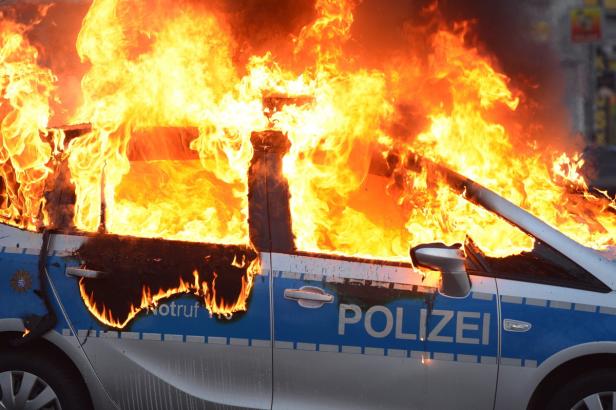 Ein Polizeiauto steht in Flammen.
