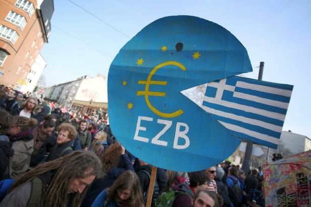 Eine Demonstration mit einem Schild, das Griechenland von der EZB „gefressen“ zeigt.