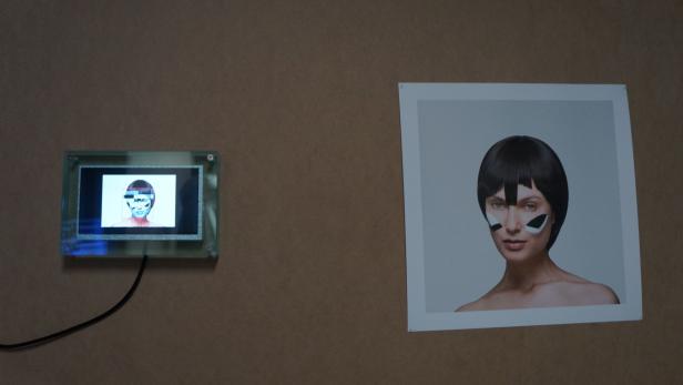 Ein Bildschirm und ein Foto zeigen ein Gesicht mit futuristischer Gesichtsbemalung.