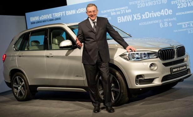 Ein Mann im Anzug posiert neben einem silbernen BMW X5 xDrive40e.