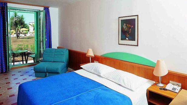 Ein Hotelzimmer mit einem Bett, einem Sessel und einem Blick auf den Garten.