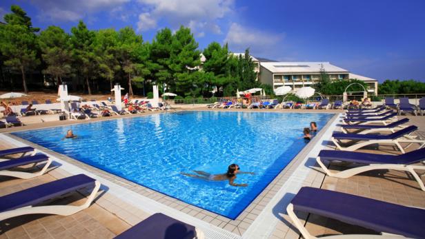 Menschen entspannen sich an einem sonnigen Tag am Pool eines Resorts.