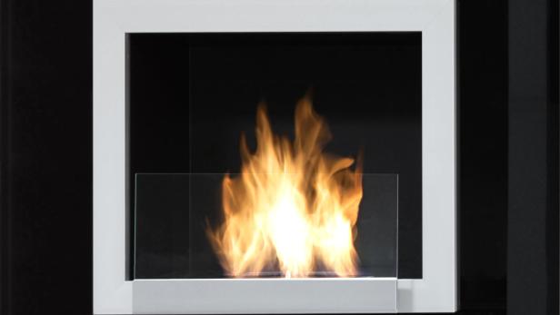 Ein moderner Kamin mit weißem Rahmen und tanzenden Flammen hinter einer Glasscheibe.