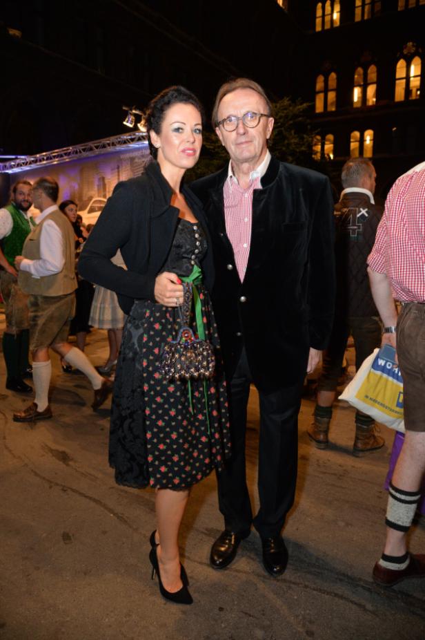 Eine Frau im Dirndl und ein Mann im Trachtenjanker posieren für ein Foto.