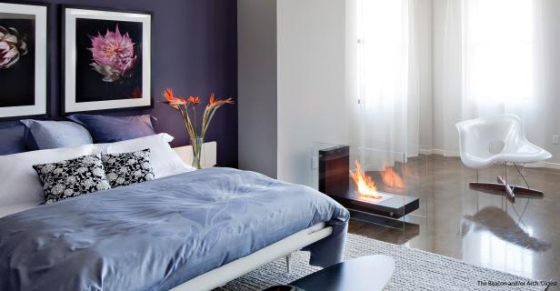 Ein Schlafzimmer mit einem Bett, einem Kamin und einem weißen Sessel.