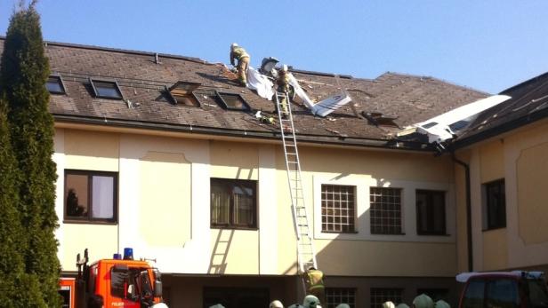 Ein Flugzeug ist in das Dach eines Hauses gestürzt, Feuerwehrleute sind im Einsatz.