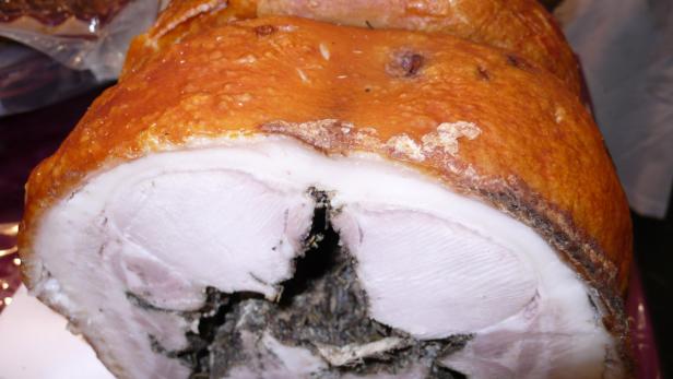 Ein Stück gefüllter Schweinebraten mit knuspriger Kruste.
