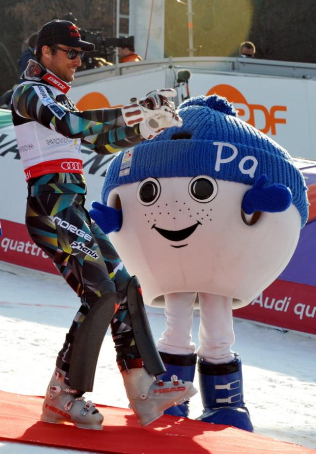 Ein Skirennläufer interagiert mit einem Maskottchen mit einer blauen Mütze.
