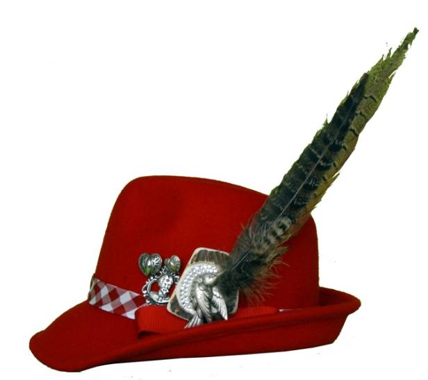 Ein roter Trachtenhut mit Feder und dekorativen Ansteckern.