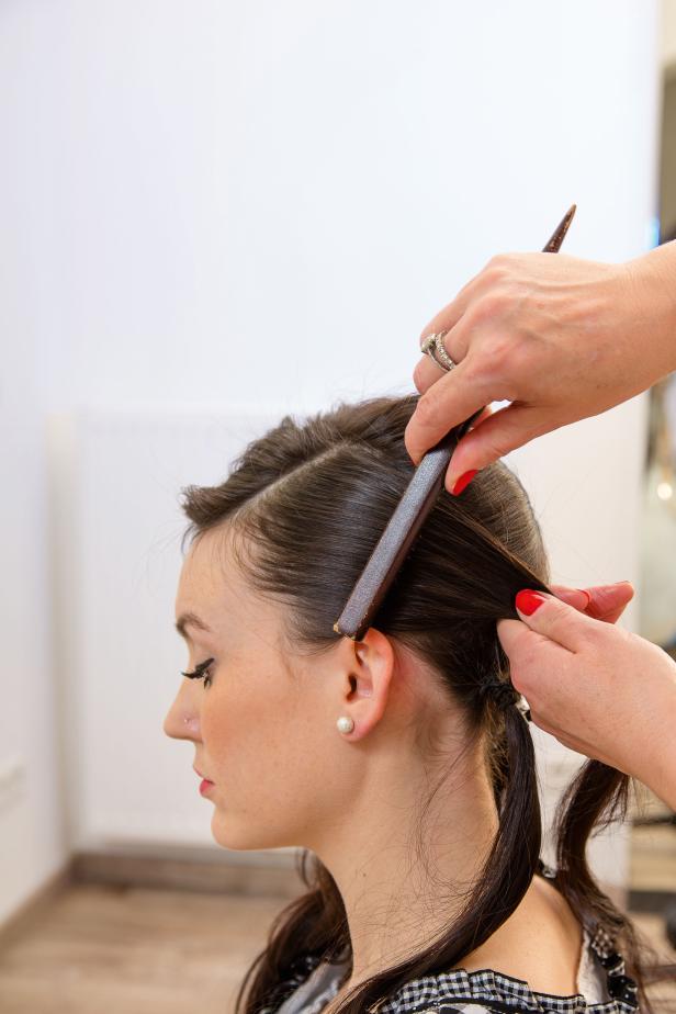 Eine Friseurin kämmt das Haar einer jungen Frau.