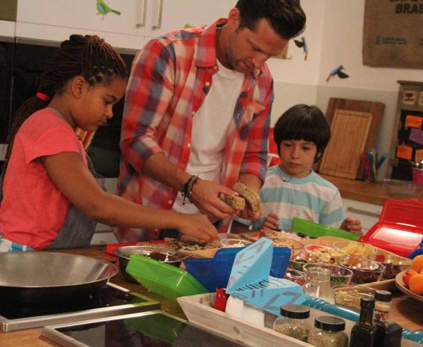 Ein Mann und zwei Kinder bereiten in einer Küche Brote zu.