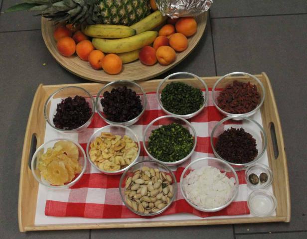 Ein Tablett mit Schüsseln mit Trockenfrüchten, Nüssen und frischen Früchten wie Ananas und Bananen.