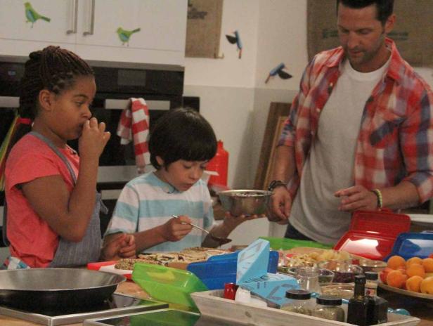 Zwei Kinder und ein Mann bereiten in einer Küche eine Mahlzeit zu.