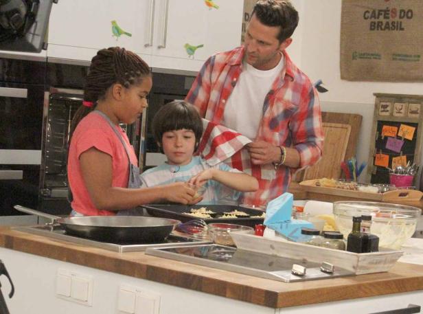 Ein Mann und zwei Kinder kochen gemeinsam in einer Küche.