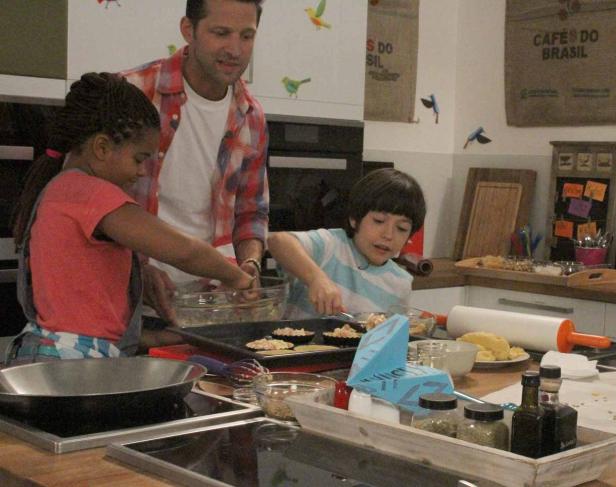 Ein Mann und zwei Kinder bereiten gemeinsam Speisen in einer Küche zu.