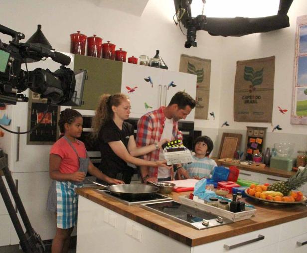 Dreharbeiten in einer Küche mit Kindern und einem Mann mit Filmklappe.