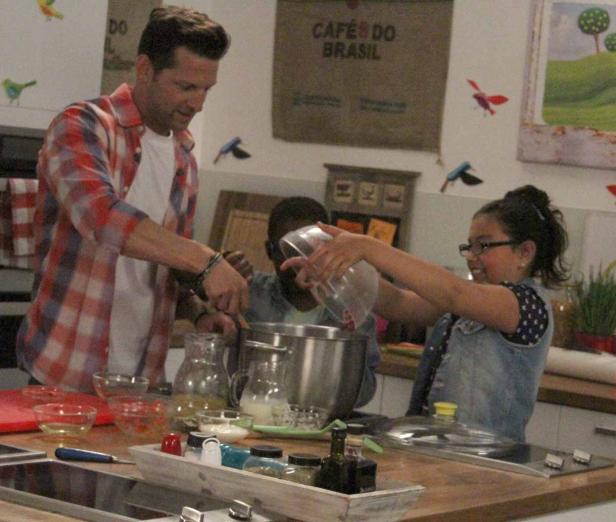 Ein Mann und zwei Kinder bereiten gemeinsam etwas in einer Küche zu.