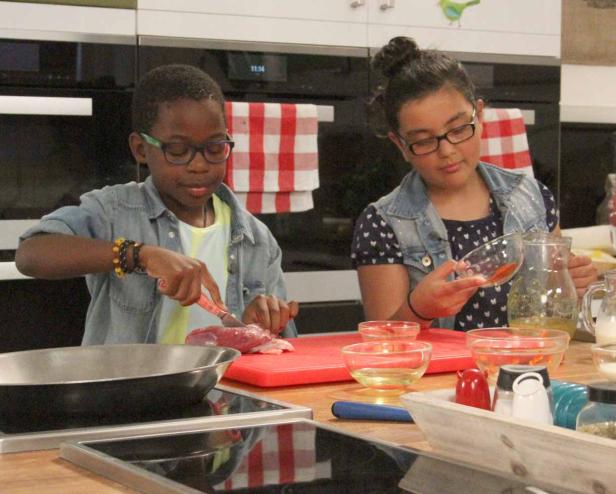 Zwei Kinder bereiten in einer Küche eine Mahlzeit zu.