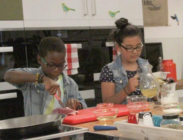 Zwei Kinder bereiten in einer Küche Speisen zu.