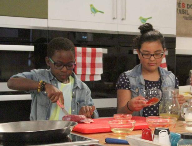 Zwei Kinder bereiten in einer Küche eine Mahlzeit zu.