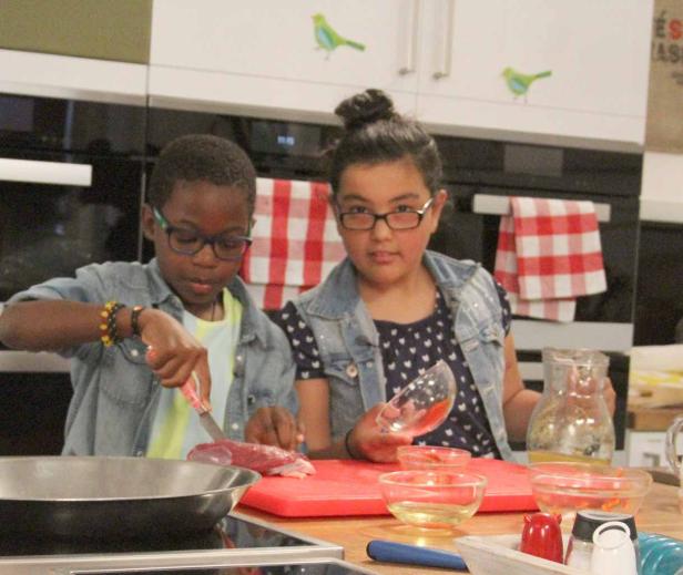 Zwei Kinder bereiten in einer Küche eine Mahlzeit zu.