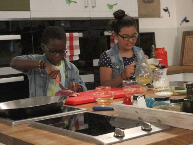 Zwei Kinder bereiten in einer Küche eine Mahlzeit zu.