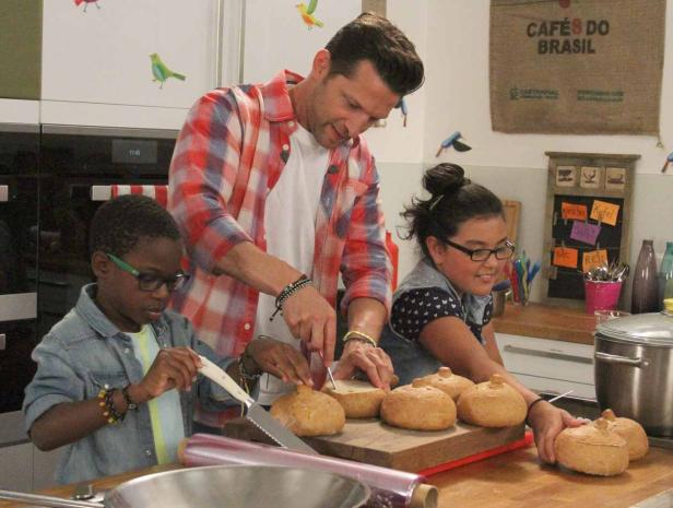 Ein Mann und zwei Kinder stehen in einer Küche und bereiten Speisen zu.