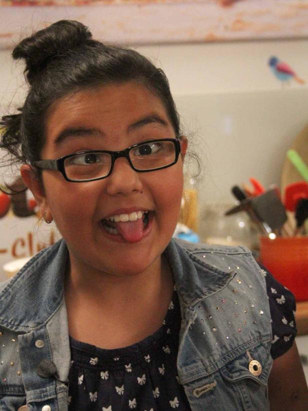 Ein junges Mädchen mit Brille streckt die Zunge heraus.