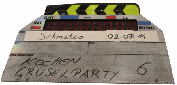 Eine Filmklappe mit den Aufschriften „Kochen Gruselparty“ und „Schmatzo“.