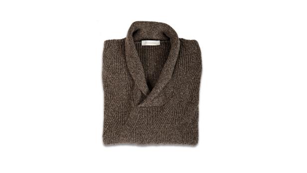 Ein gefalteter, brauner Strickpullover mit Schalkragen liegt auf einem weißen Hintergrund.