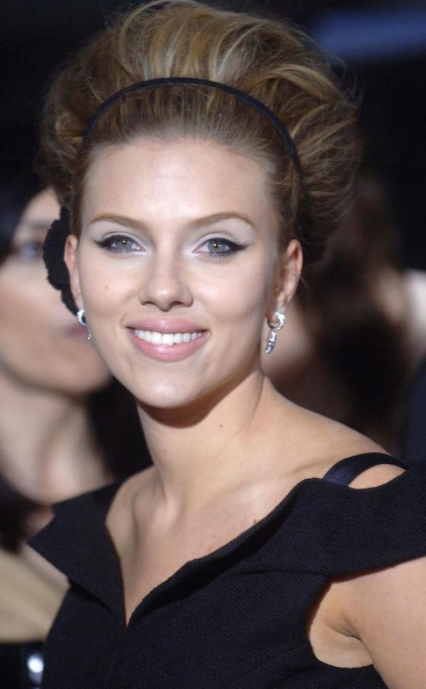 Scarlett Johansson lächelt in einem schwarzen Kleid mit hochgesteckten Haaren.