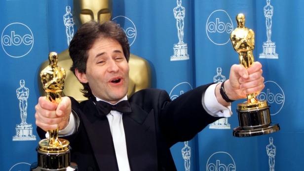 Hans Zimmer hält freudestrahlend zwei Oscars in den Händen.