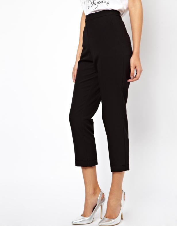 Eine Frau trägt eine schwarze Hose und silberne High Heels.