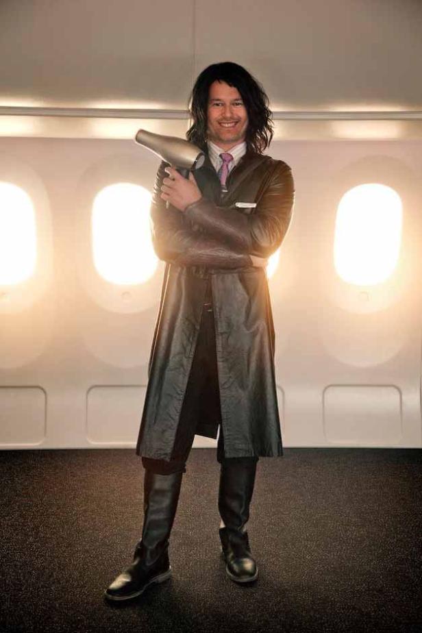 Ein Mann in einem Flugzeug hält einen Fön im Arm.