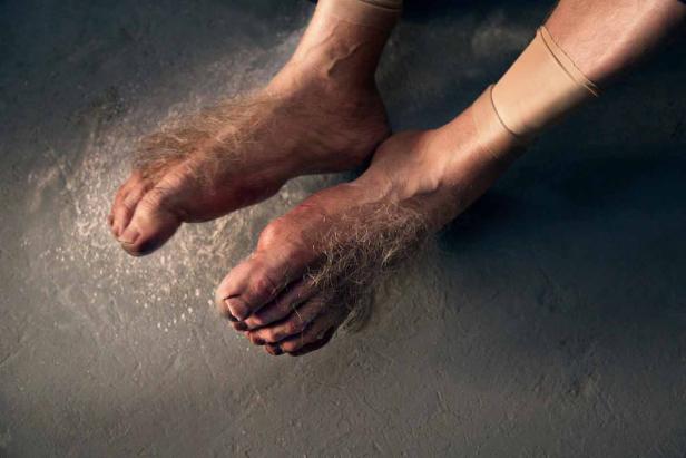 Ein Paar behaarte Füße stehen auf einem grauen Untergrund.