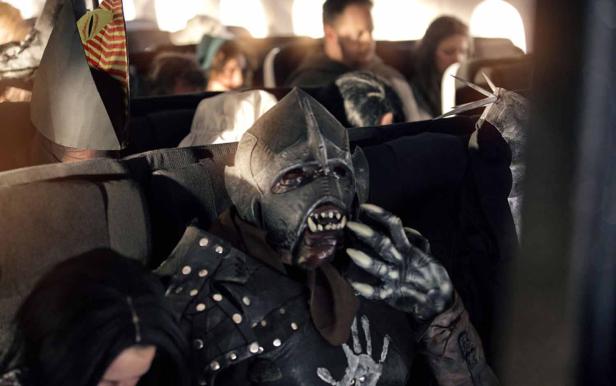 Ein als Ork verkleideter Mann sitzt in einem Flugzeug.