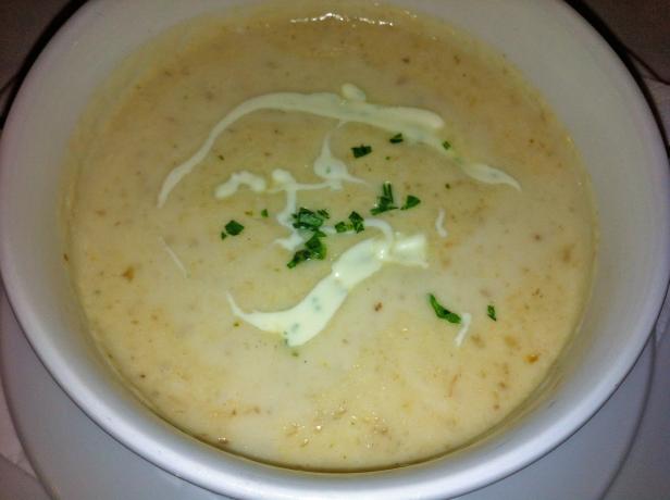 Eine Schüssel cremige Suppe, garniert mit einem Klecks Creme und Petersilie.