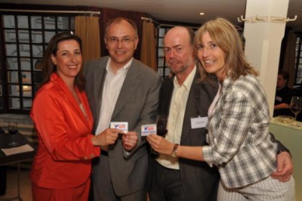 Vier Personen posieren mit Visitenkarten bei einer Veranstaltung.