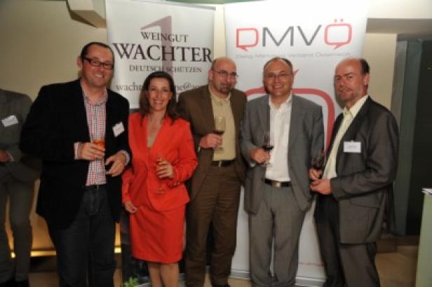 Eine Gruppe von Personen posiert mit Weingläsern vor Bannern von „Weingut Wachter“ und „DMVÖ“.