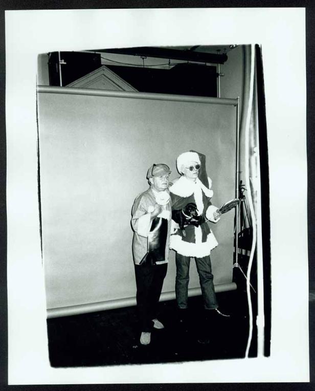 Zwei Personen posieren in Kostümen vor einem neutralen Hintergrund.