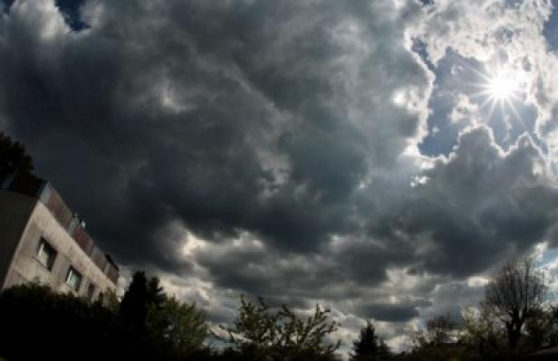 Dramatische dunkle Wolken ziehen über ein Wohngebiet, während die Sonne durchbricht.