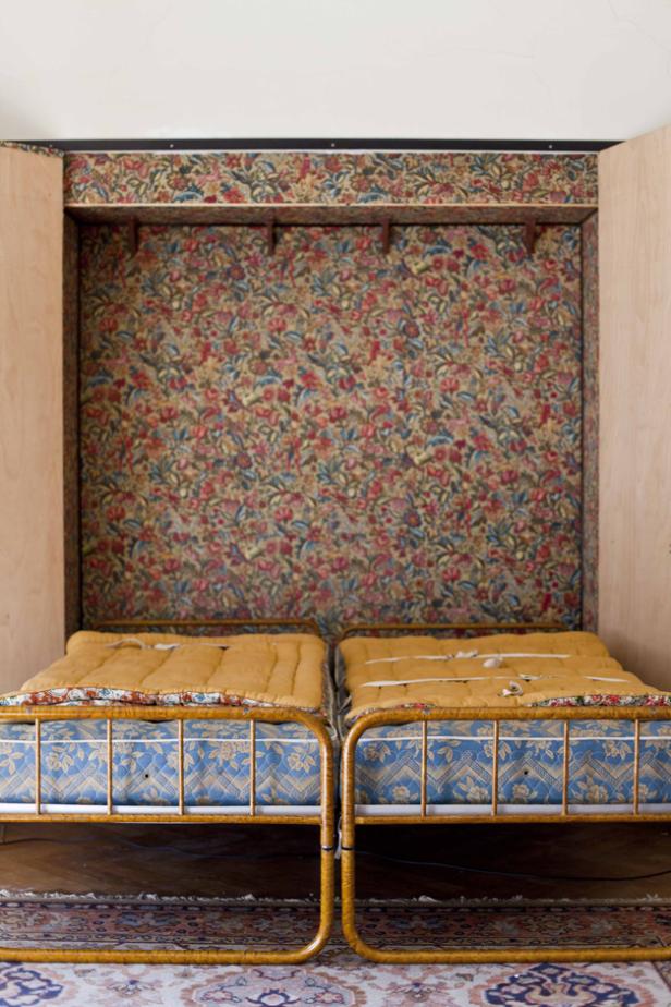 Zwei Betten mit floral gemusterten Wänden stehen in einem Raum.