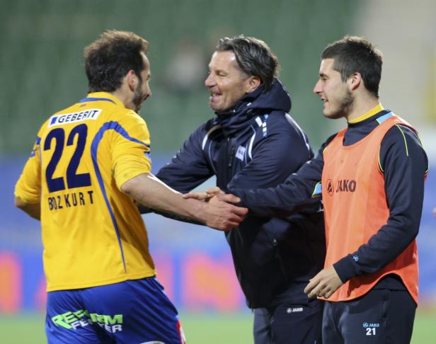 Ein Trainer schüttelt die Hände zweier Fußballspieler.