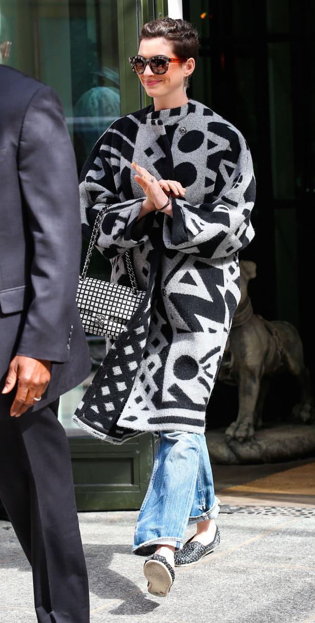 Anne Hathaway trägt einen gemusterten Mantel, Jeans und eine Chanel-Tasche.