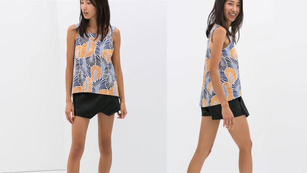 Eine Frau trägt ein ärmelloses Oberteil mit Muster und schwarze Shorts.