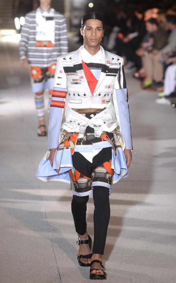 Ein Mann auf einem Laufsteg präsentiert ein extravagantes Outfit mit geometrischen Mustern.