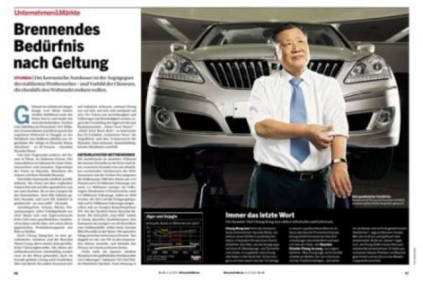 Ein Mann steht vor einem silbernen Auto, das auf einer Hebebühne steht.