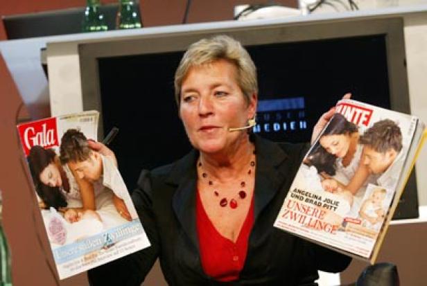 Eine Frau präsentiert Zeitschriften mit Angelina Jolie, Brad Pitt und ihren Zwillingen.
