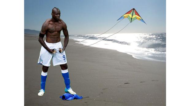 Mario Balotelli steht am Strand und lässt einen Drachen steigen.